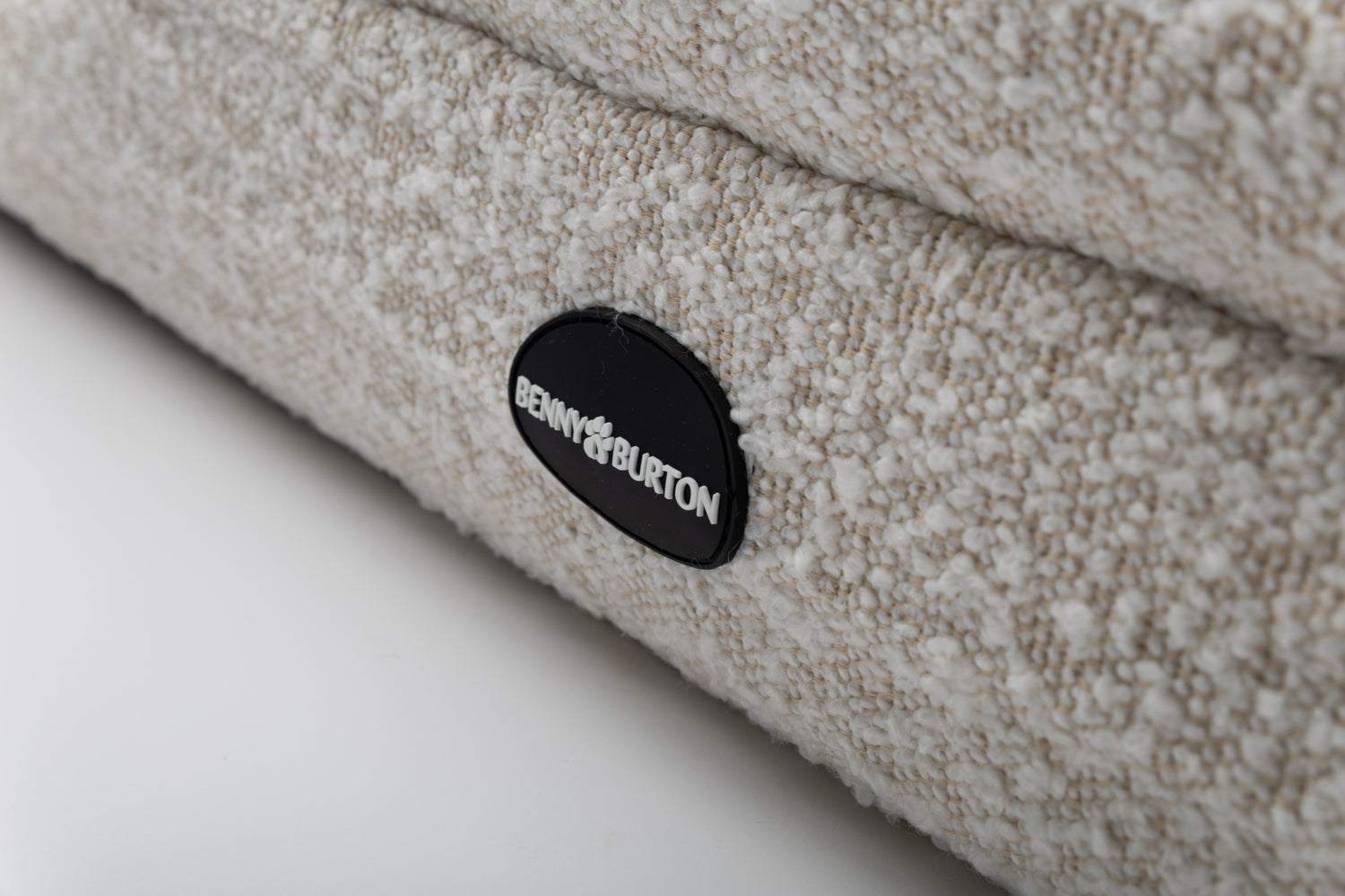 Close-up of textured beige Bouclé fabric and Benjy & Burton logo on Hundebett Barklay S dog bed with washable cover and memory foam mattress