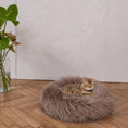 Load image into Gallery viewer, Rundes handgemachtes Hundekissen mit Naturfüllung aus langem Schaffell in taupe mit Katze
